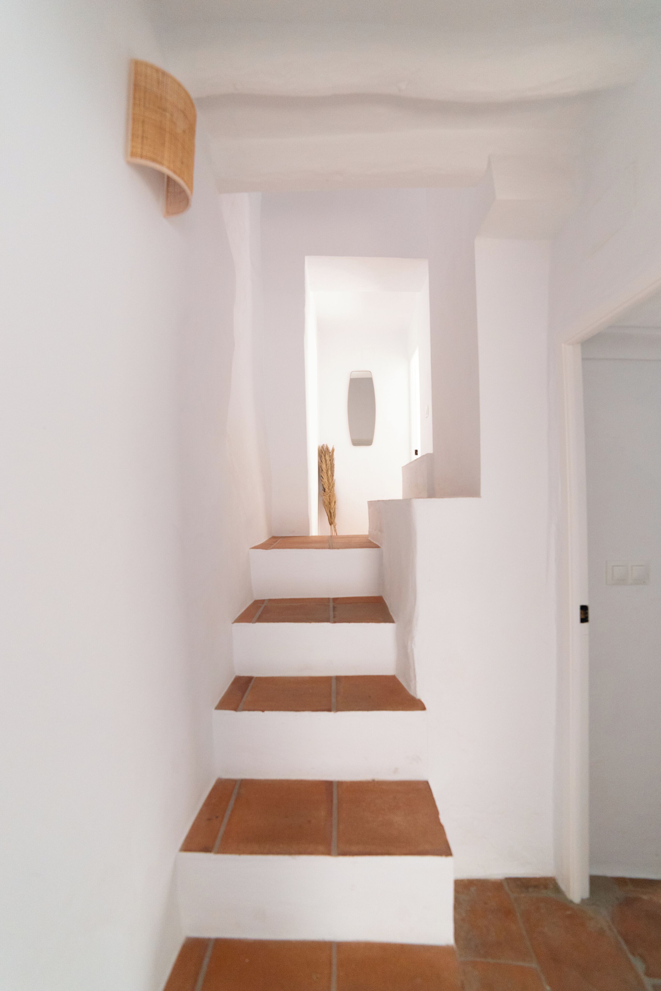 Eine Treppe mit weißen Wänden und braunen Stufen, die zu einer Tür führt.