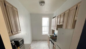 A compact kitchen with light wood cabinets, a microwave, a stove, and a refrigerator. - 3-bedroom condo in Central Park, Manhattan, Times Square!
 (New York)