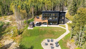 A modern two-story house with a deck and outdoor seating area.