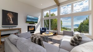 A modern living room with a fireplace, large windows, and a cozy seating area.
