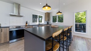 Una cocina moderna con una isla grande, armarios de madera, electrodomésticos de acero inoxidable e iluminación colgante.