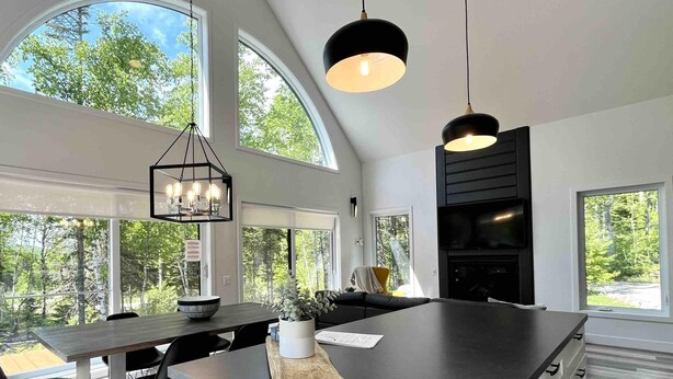 Une cuisine moderne dotée de grandes fenêtres, d’un îlot central et de luminaires suspendus.