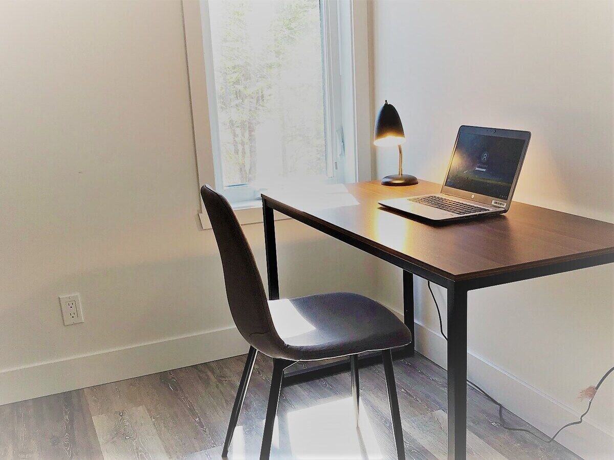Une petite pièce avec un bureau, une chaise et un ordinateur portable.