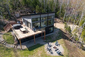 Une cabane moderne à deux étages, dotée d’une terrasse et d’un espace salon extérieur.