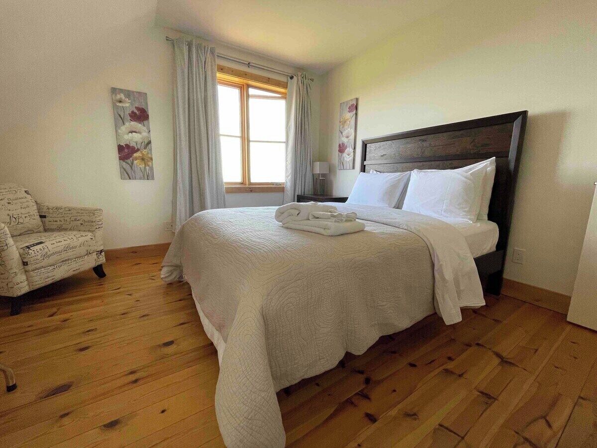 Une chambre à coucher avec un grand lit, une chaise et une fenêtre avec des rideaux.
