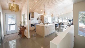 A modern kitchen with wooden ceiling, a central island, and pendant lighting. - Chez Annie 215: Panoramic Views & Hot Tub (Charlevoix)