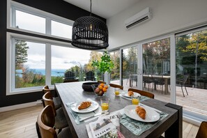 A dining area with a table set for breakfast, large windows, and a view of the outdoors.