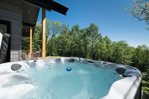 Relax in the backyard hot tub surrounded by a tree-lined view.