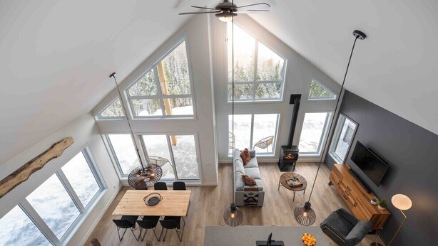 Amplio espacio tipo loft con grandes ventanales, una mesa de comedor, un sofá y un televisor.