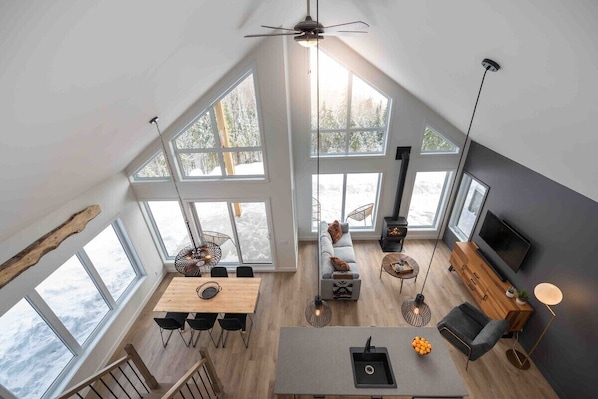 Enjoy expansive views of the surrounding landscape from this open-plan living space with a high ceiling and large windows.