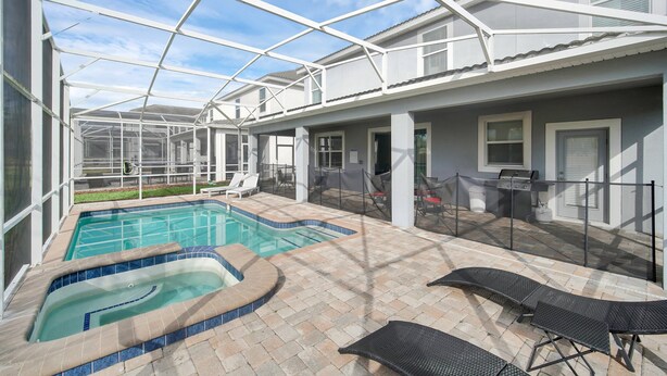 Ein überdachter Pool im Freien mit Liegestühlen und Grillplatz.