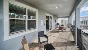 Ein überdachter Außenbereich mit Sitzgelegenheit, Grill und einem Schild mit den Terrassenregeln.