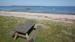 A beach with a wooden picnic table, a sandy shore, and a calm sea. - 4 Star Holiday Home in Aabenraa (Aabenraa)
