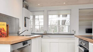 A modern kitchen with white cabinetry, a wooden countertop, and a window above the sink. - 4 Star Holiday Home in Aabenraa (Aabenraa)