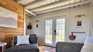 A cozy room with two grey sofas, a wooden ceiling, and a door leading outside. - Lillian’s blackberry cabin (Ava)