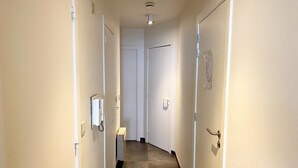 A narrow hallway with two doors, a light switch, and a wall-mounted telephone. - Apartment in Nieuwpoort by the Beach (Nieuwpoort)
