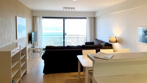 A modern hotel room with a large window, a sofa, a TV, and a desk. - Apartment in Nieuwpoort by the Beach (Nieuwpoort)