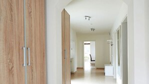 A corridor with wooden wardrobes and a tiled floor, leading to a bright room with a chair and a desk. - Rheinflair Comfortable Holiday Residence (Kamp-Bornhofen)