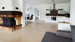A spacious living area with a fireplace, a dining area, and a kitchen with modern appliances. - Rheinflair Comfortable Holiday Residence (Kamp-Bornhofen)