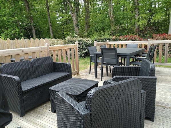 An outdoor patio with wicker furniture, including a sofa, chairs, and a table.