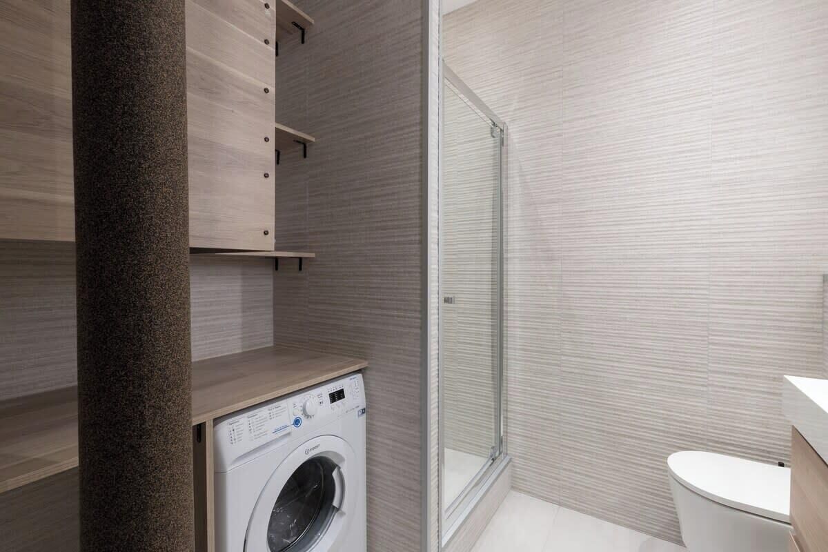 Un baño moderno con lavadora integrada, inodoro y zona de ducha.