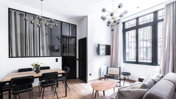 Ein modernes Wohnzimmer mit Sofa, Couchtisch und Essbereich mit Tisch und Stühlen.