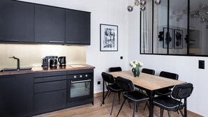 Eine moderne Küche mit dunklen Schränken, einer Holz Arbeitsplatte und einem Essbereich mit schwarzen Stühlen und einem Holztisch.