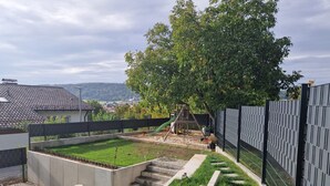 Ein Garten mit Spielbereich, einer Betonstiege und einem umzäunten Bereich.