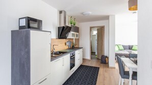 Eine kleine Küche mit Mikrowelle, Herd und Spüle. Es gibt einen Essbereich mit Tisch und Stühlen.
