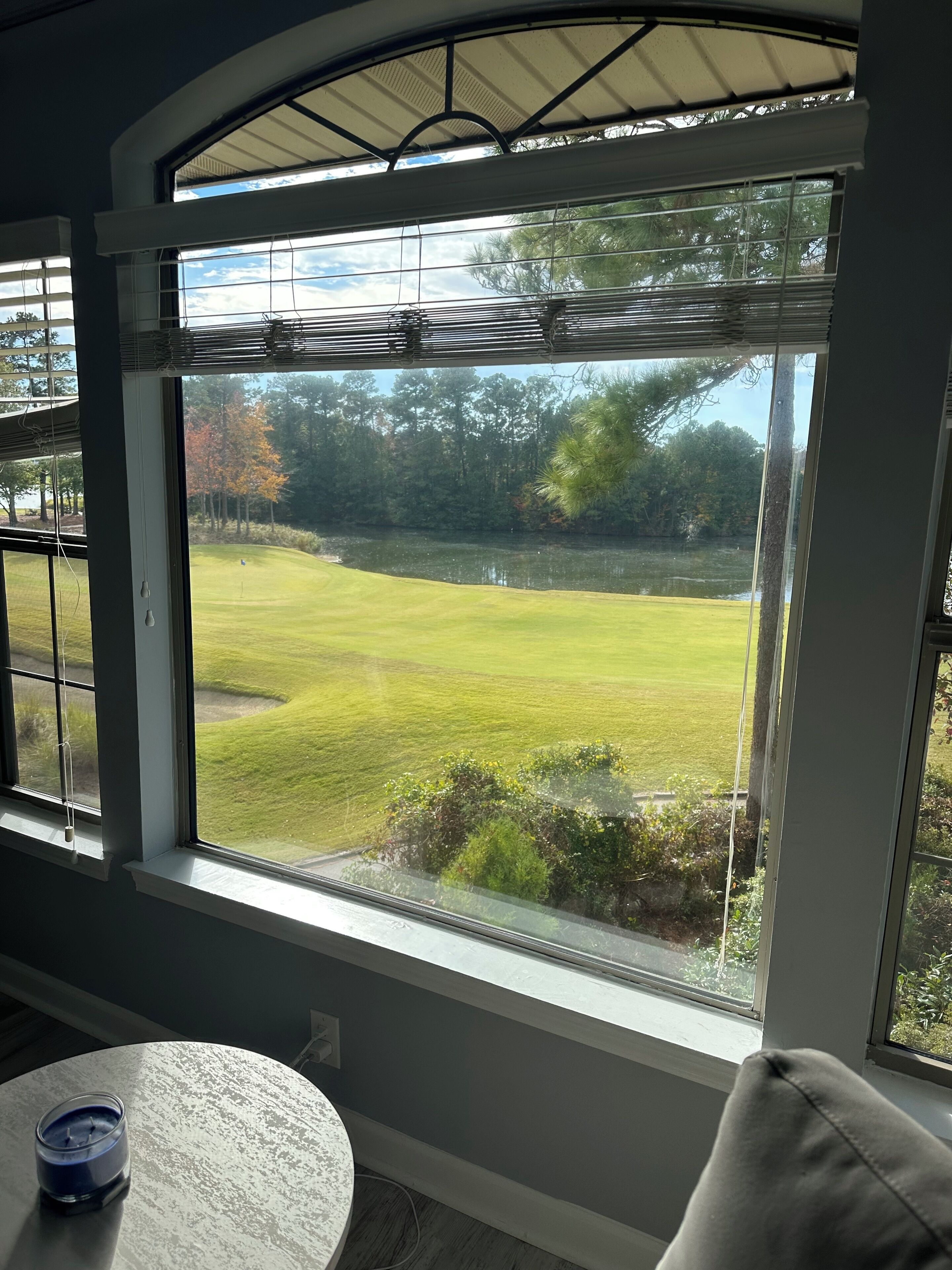 A room with a large window overlooking a grassy area and trees.