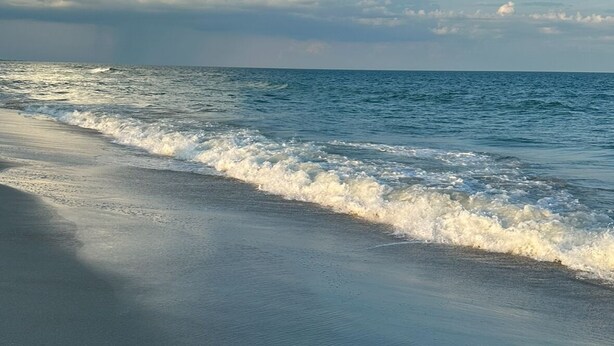 A beach with waves and a clear sky.