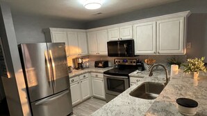 A modern kitchen with white cabinets, stainless steel appliances, a granite countertop, and a built-in oven.