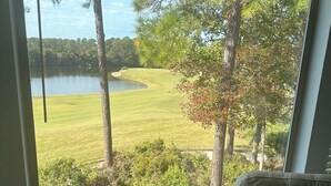 A room with a large window overlooking a lake and a grassy area with trees.