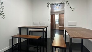 A room with a black floor, white walls, and a ceiling light. There are two tables and two benches.