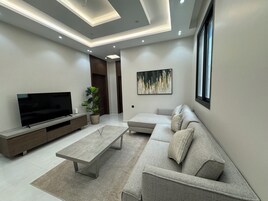 Deluxe Apartment, 3 Bedrooms, Kitchenette | Living area | 55-inch Smart TV with digital channels