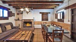 A cozy living room with a fireplace, wooden furniture, and a dining area with a glass table. - Country House Near Sierras Subbeticas Park (Montefrio)