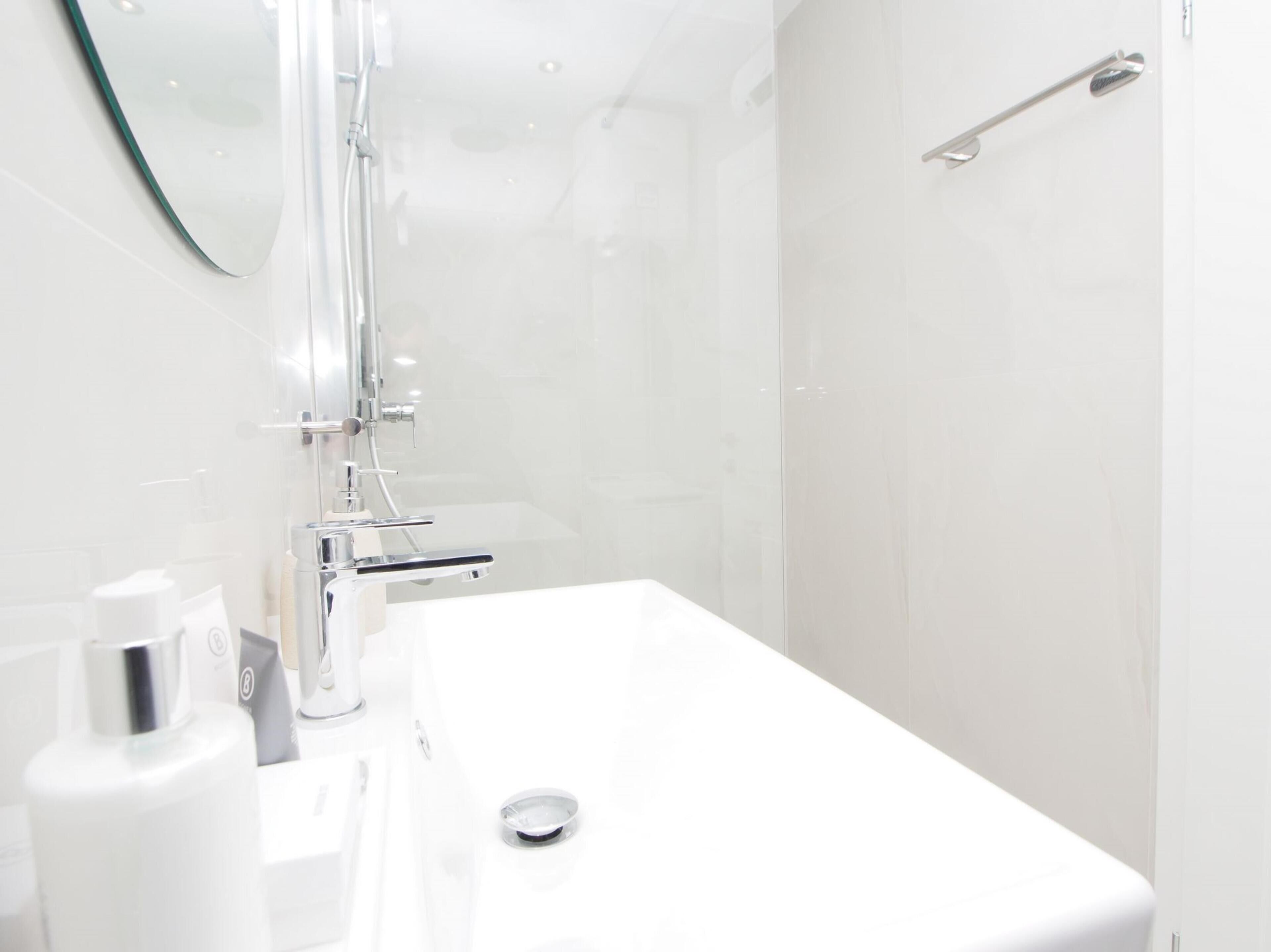 A modern bathroom with a white sink, chrome fixtures, and a glass shower enclosure.