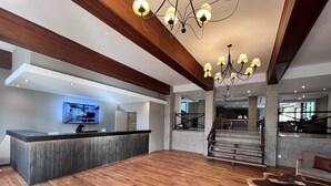 A spacious lobby with a wooden reception desk, a modern chandelier, and a staircase leading to an upper level. - Cerro Calafate Hotel (El Calafate)