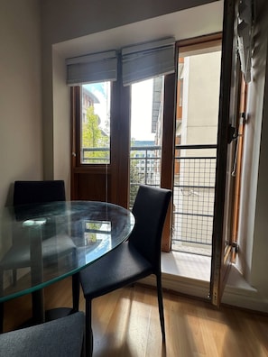 Enjoy meals at the glass-top dining table with two chairs, and step out onto the balcony for a view of the surrounding area.