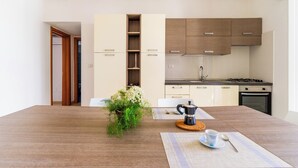 Una cucina moderna con mobili in legno, un fornello a gas e una moka sul tavolo.