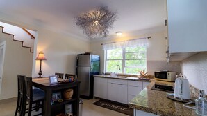 Une cuisine compacte comprenant un coin repas, un réfrigérateur, un four à micro-ondes et un lustre.