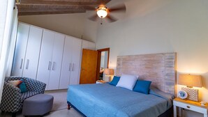 Une chambre à coucher comprenant un lit, une chaise, une armoire et un ventilateur de plafond.
