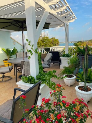 An outdoor patio area with a pergola, seating, and potted plants.