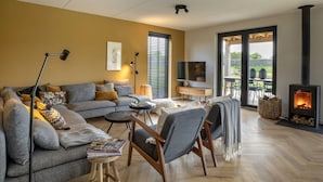 Una sala de estar moderna con un sofá, sillones, una mesa de centro, un televisor y una chimenea.