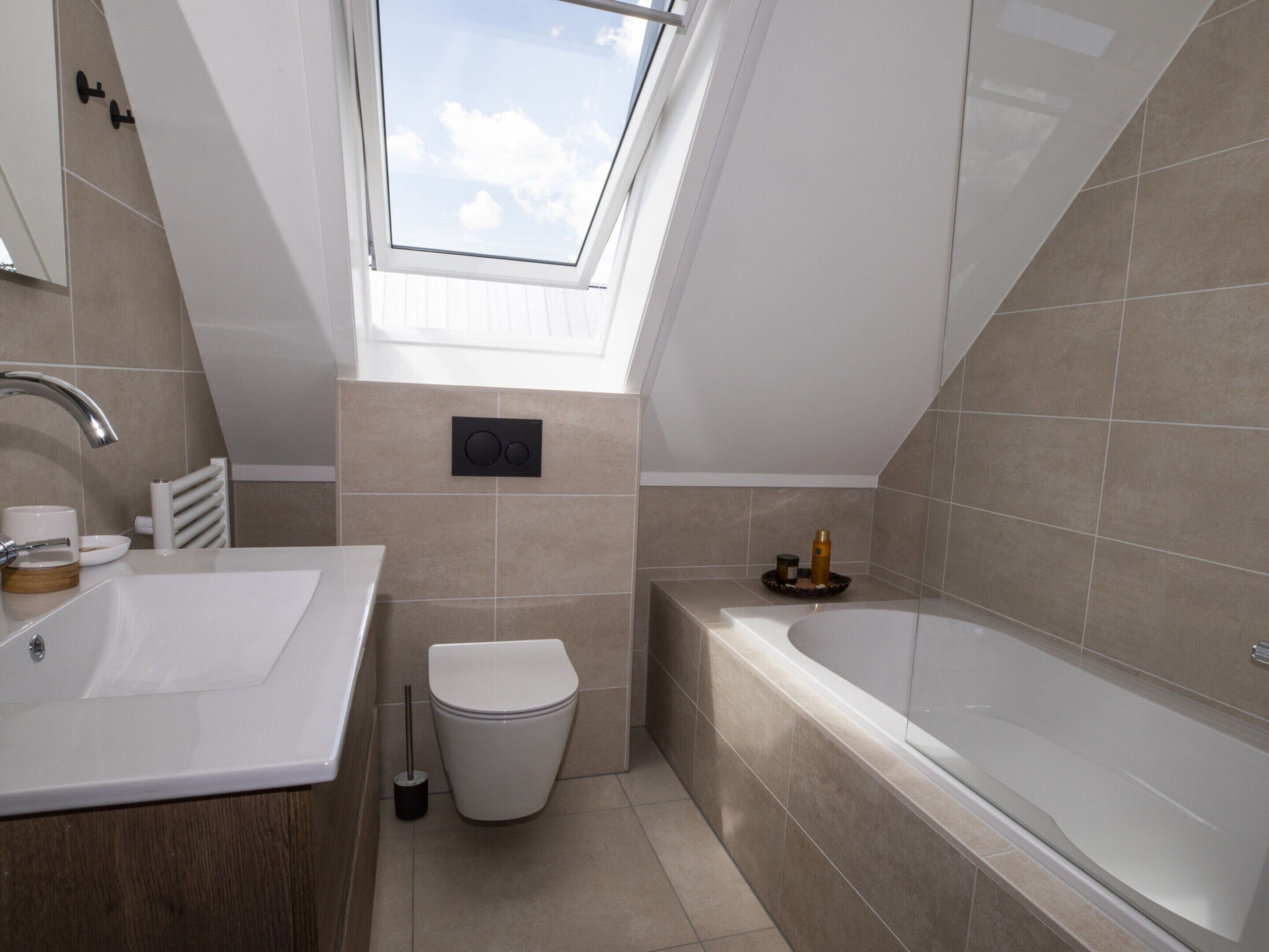 A modern bathroom with a skylight, a bathtub, and a toilet.