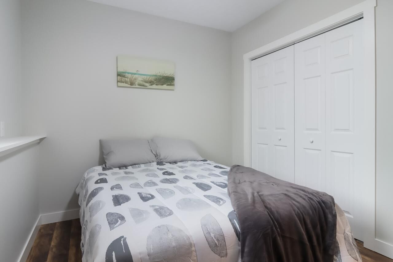 Une chambre à coucher avec un lit, un tableau accroché au mur et une armoire blanche.