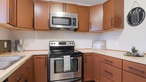 Una cocina con armarios de madera, un microondas de acero inoxidable y un horno doble.