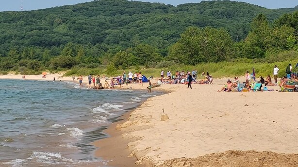 Una playa con gente relajándose y paseando por la orilla.
