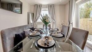 A dining area with a glass table set for four, surrounded by cushioned chairs.