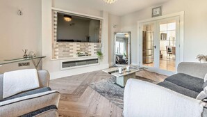 A modern living room with a fireplace, a large TV, and comfortable seating.